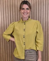 Camisa de algodón color blanco, con cuello alto con volados, mangas tres cuartos con detalles de bordado ingles y cierre frontal con botones de nácar.