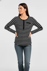 Remera de manga larga con cuello redondo y abertura frontal con botones. Presenta un patrón de rayas horizontales blancas y negras, y un pequeño bolsillo negro en el pecho.