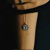 Collar de cadena fina de eslabones con dije circular grabado con la figura de un ángel.