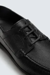 Zapato tipo náutico confeccionado en piel con horma redonda, cordones de piel y suela a tono.