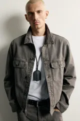 Cazadora de denim de algodón en color gris oscuro con efecto lavado, corte relaxed fit, cuello camisero, bolsillos delanteros con solapa en el pecho y cierre frontal con botones.