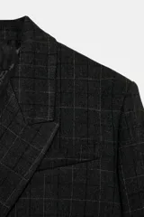 Blazer corto de corte oversize con estampado de cuadros, cuello con solapas de muesca y manga larga. Presenta cierre frontal cruzado con un botón y falsos bolsillos de vivo en el delantero. Incluye forro interior.