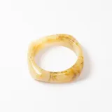 Brazalete rígido de resina con efecto marmolado en tonos beige y crema.