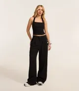 Pantalón wide leg negro confeccionado en algodón, con pliegues delanteros y cierre por botón y cremallera.