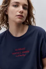 Remera blanca de silueta amplia y calce relajado, confeccionada en tela suave y liviana, con cuello redondo, mangas cortas con vuelta y hombros caídos. Cuenta con un delicado bordado frontal en color azul con la inscripción "LE SOLEIL TOUTE L'ANNÉE sur la Côte d'Azur".