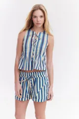 Blusa sin mangas de algodón con rayas verticales en tonos amarillo, azul y bordó. Presenta escote redondo con aberturas y cordones ajustables para hacer moñas en el frente, además de detalles de tablas en la parte superior.