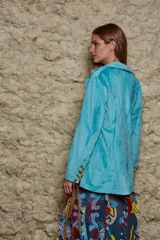 Blazer celeste de terciopelo con corte al cuerpo y detalles de cuero marrón en la parte delantera y en los puños.