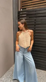 Top halter color beige, estilo chaleco corto, con cuello alto y bordes festoneados con costura decorativa.