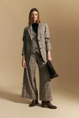 Blazer de corte sastrero con estampado de cuadros en tonos beige, marrones y rojizos. Presenta solapas clásicas, cierre frontal con un botón y bolsillos laterales con solapa.