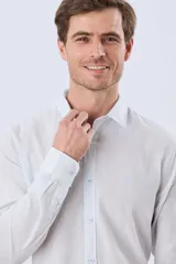 Camisa de lino a rayas finas en tonos beige y blanco, de manga larga con puños vueltos, cuello camisero y cierre frontal de botones. Cuenta con un pequeño logo bordado en el pecho.