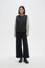 Chaleco acolchado de color negro con diseño de rombos, cierre frontal con botones metálicos a presión y dos bolsillos delanteros aplicados.