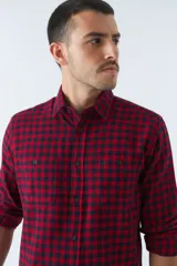 Camisa de viyela a cuadros negros, blancos y rojos, de corte slim fit, con bolsillos en el pecho, manga larga y cierre con botones.