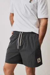 Short de baño color gris oscuro, con cintura elástica ajustable mediante cordones blancos y un pequeño parche decorativo en el borde inferior.