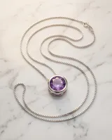 Collar de plata 925 con cadena fina y dije redondo tipo punto de luz con circonia central en color violeta.