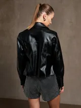 Campera negra de cuero sintético, corte entallado, con cierre frontal y cuello clásico.