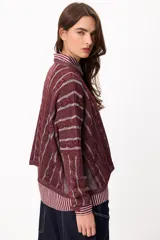 Sweater de punto con diseño de rayas verticales en relieve y textura trenzada, color terracota y beige. Presenta cuello redondo, corte holgado y diseño cropped.