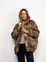Campera tipo bomber con estampado floral estilo tapicería en tonos oscuros, con cuello clásico, cierre frontal con botones metálicos y bolsillos laterales.