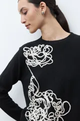 Sweater de punto color rojo melange, con cuello redondo, manga larga y detalle de bordado floral en relieve en color crudo en el frente.