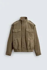 Cazadora de corte relajado confeccionada en piel con acabado de ante. Presenta cuello subido, cierre frontal con cremallera oculta bajo solapa con botones a presión, bolsillos de plastrón con solapa en el pecho y bajo con elástico. Incluye trabillas en los hombros y puños con botón.