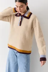 Buzo de lana tipo polo con cuello y cartera de botones en colores contrastantes. Presenta mangas con textura de ochos y puños y ruedo con terminaciones en franjas de colores.