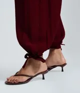 Pantalón estilo aladino color bordó, confeccionado en tejido crepé con textura. Presenta cintura elástica, corte holgado en las piernas y ruedo ajustado con lazo decorativo.