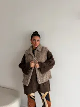 Chaleco de peluche en tono beige, con cierre frontal, cuello solapa y bolsillos laterales.