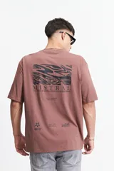 Remera marrón de manga corta con corte oversize y cuello redondo. Estampado en la espalda con diseño abstracto y texto.