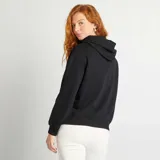 Buzo negro liso con capucha, cordones ajustables y bolsillo tipo canguro.