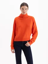 Polera de tejido de punto color naranja, con cuello alto, manga larga y diseño holgado.