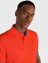 Chomba naranja de Tommy Hilfiger, corte regular, con cuello tipo chomba, cartera de dos botones, logo de la marca bordado en el pecho y mangas cortas.