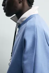 Sudadera azul con corte relaxed fit, cuello redondo y mangas largas con puños de rib, confeccionada en tejido con mezcla de algodón y acabado afelpado en el interior.