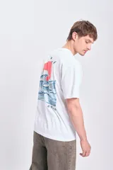 Camiseta blanca de manga corta con corte oversize y estampa en la espalda de una ola, un sol y tres aves. Incluye texto en japonés.