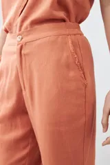 Pantalón capri color durazno de lino con efecto desflecado en el ruedo.