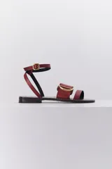 Sandalias planas de cuero color bordó, con dos tiras anchas sobre el empeine y tira fina con hebilla alrededor del tobillo.