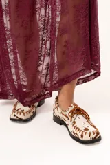 Zapato náutico de horma cuadrada confeccionado en cuero de pelo de vaca con estampado animal print. Presenta detalles de pasamanería en cuero descarne en el frente y laterales, cordones frontales y suela plana con pequeño taco.