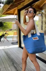 Bolso de playa azul con asas anchas color crema y etiqueta de cuero marrón.