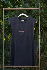 Musculosa sin mangas, color azul celeste con efecto acid wash, cuello redondo y amplias sisas. Presenta un pequeño estampado frontal de tres hongos rojos y blancos con la inscripción "Tuya" debajo.