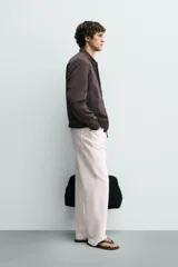 Cazadora bomber ligera de tejido técnico color verde oliva, con cuello, puños y bajo en rib elástico. Presenta cierre frontal de cremallera y bolsillos de vivo en la cadera.