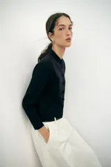 Chaqueta de punto negra de cuello redondo y manga larga, con bolsillos delanteros de parche y cierre frontal con alamares.