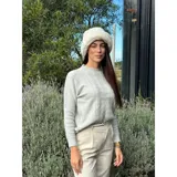 Sweater de punto color blanco marfil, con diseño de trenzas frontales, cuello redondo y mangas largas con puños elásticos acanalados.