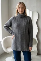 Sweater de punto gris con cuello alto, diseño acanalado y corte oversize de manga larga.