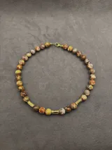 Collar Ound modelo Guayabo, elaborado con cuentas esféricas de piedra en tonos verdosos y marrones, intercaladas con separadores cilíndricos dorados. Cierre de mosquetón dorado.