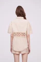 Camisa blanca de algodón con apliques de crochet calado en la cintura, manga corta y cuello camisa.