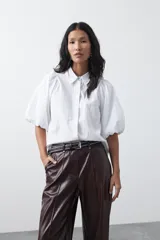 Pantalón de cuero sintético en color marrón oscuro, con corte flare, tiro medio y costuras frontales verticales que estilizan la silueta.