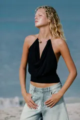 Top de poliamida color negro con escote drapeado y cuello halter que incorpora un detalle de choker metálico dorado.