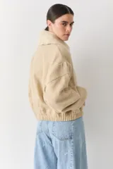 Campera bomber de paño color beige, con cierre frontal, cuello alto y puños elásticos.