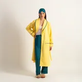 Bata clásica amarilla con textura capitoné y ribete verde en cuello, solapa, puños y cinturón.