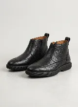 Bota corta de cuero negro con textura granulada, diseño de puntera reforzada y suela de goma gruesa con relieve estriado. Cuenta con cierre lateral y tirador en la parte trasera.