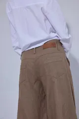 Pantalón de tiro medio y piernas anchas, confeccionado en mezcla de lino y algodón, con bolsillos delanteros y traseros con detalles de costuras pespunteadas a contratono.