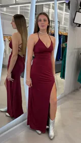 Vestido largo bordó con brillo, de corte sirena, escote en V y tirantes finos cruzados en la espalda. Cuenta con un tajo lateral profundo en la pierna.